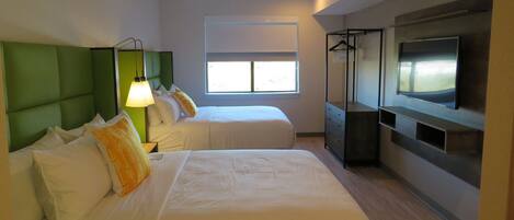 A hotel room with two beds, a TV, a window, and a wardrobe.