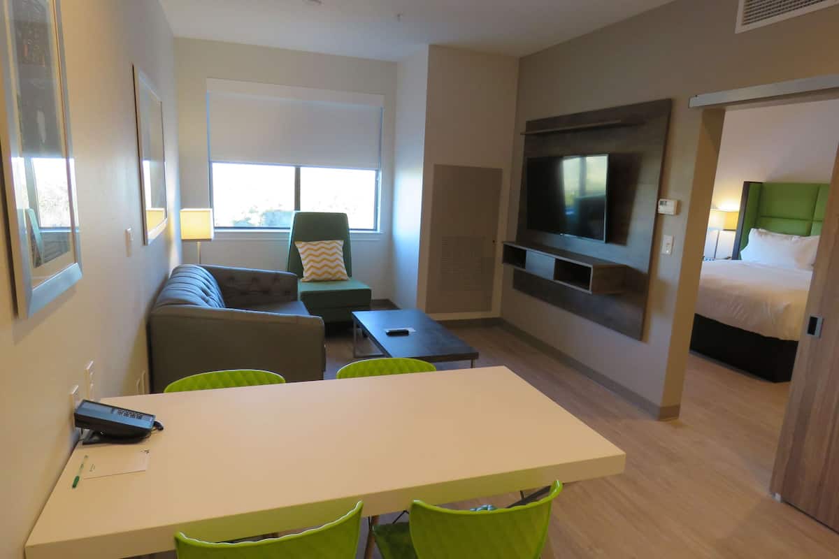 Een hotelkamer met een bank, een eettafel, stoelen, een televisie en een bed.
