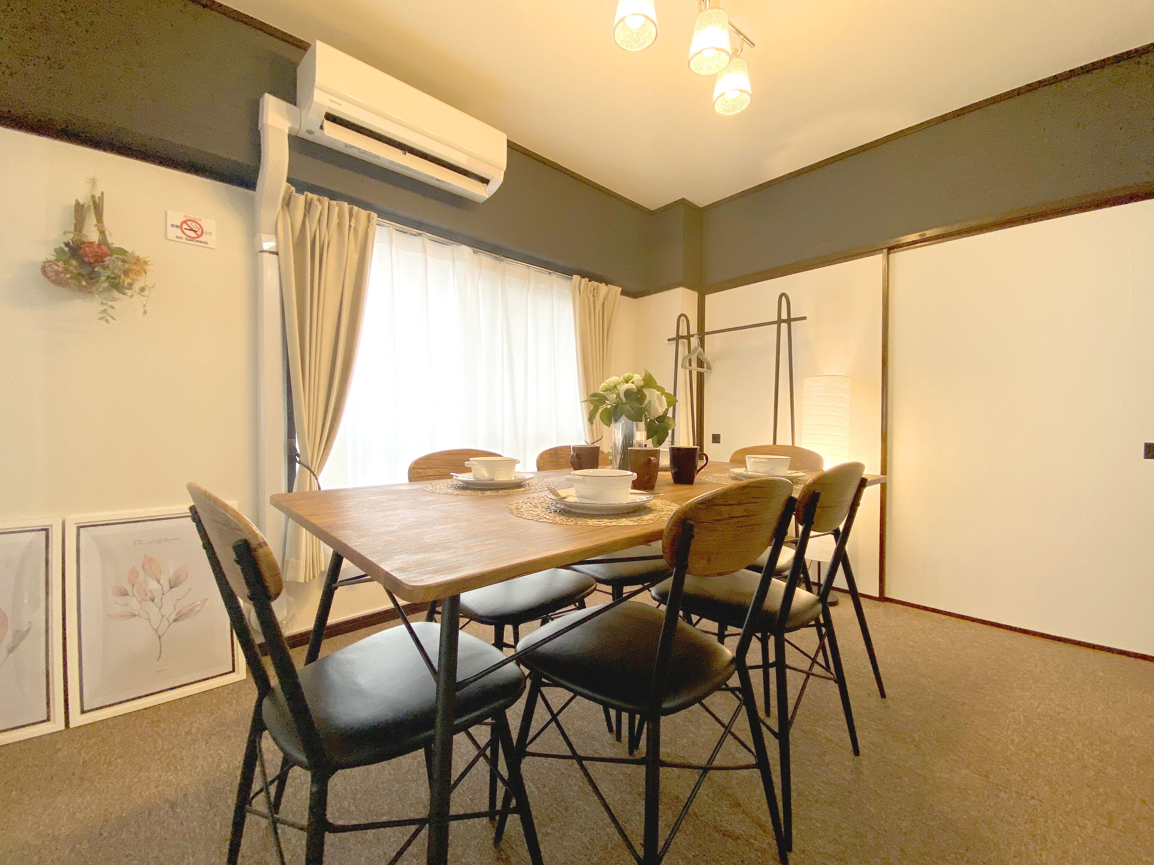 Een eethoek met een houten tafel, zwarte stoelen en een potplant.