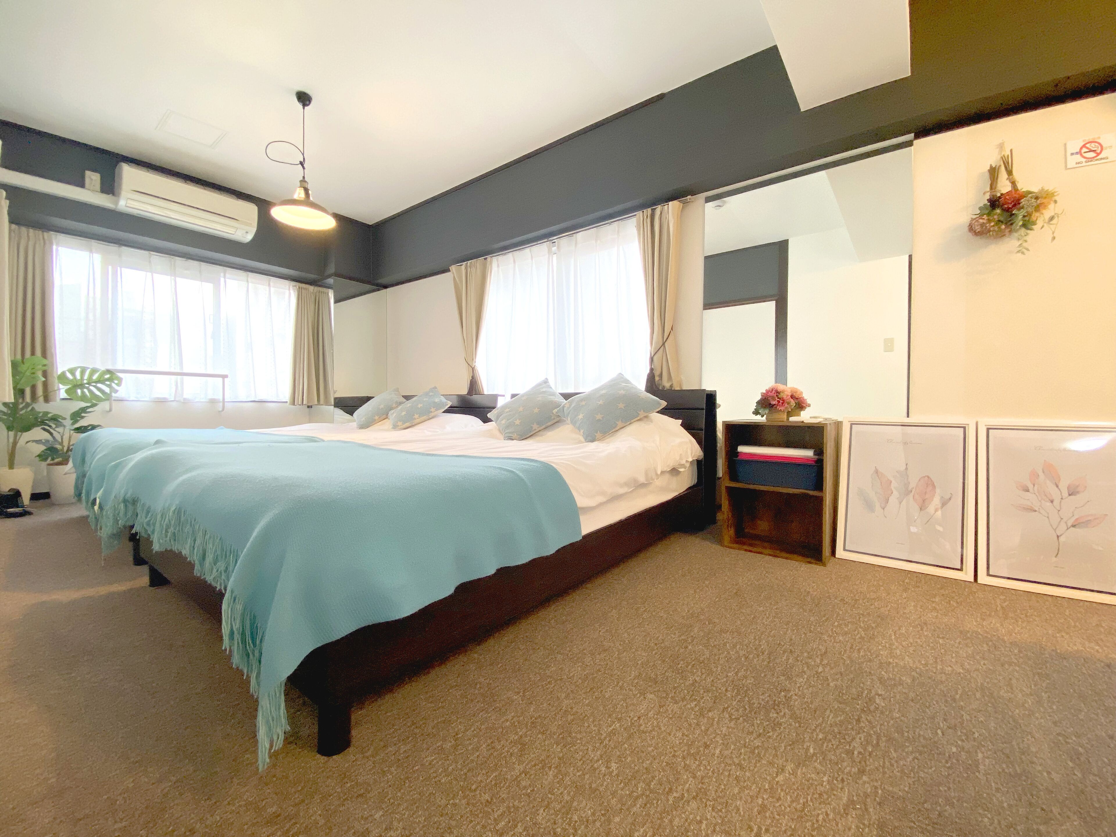 A bedroom with a bed, a nightstand, a mirror, and a window with curtains.