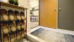 Un zapatero con varios pares de zapatos, una puerta de madera y una alfombra pequeña en un pasillo.