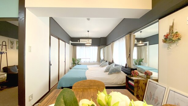 Una habitación de hotel con una cama grande, una mesa de madera con un florero y un espejo en la pared.