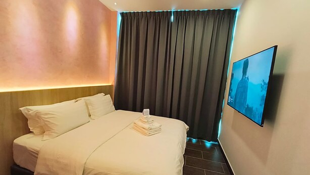 Une chambre d’hôtel équipée d’un lit, d’un téléviseur à écran plat et d’une grande fenêtre avec des rideaux.