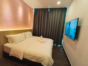 A hotel room with a bed, a flat-screen TV, and a large window with curtains.