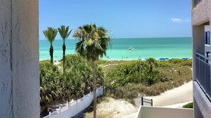A balcony with a view of a beach, palm trees, and a boat on the water. - Location, location! Private Beach, Gulf Views from Balcony, Heated Pool, Siesta Sands with King Bed (Sarasota)