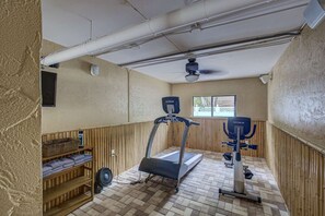 Ein kleiner Fitnessraum mit Laufband, Ergometer und Ventilator.
