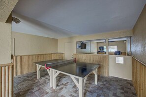 A ping pong table in a room with a tiled floor and a wall-mounted television. - Siesta Sands Private Beach | Gulf Views | Htd Pool (Sarasota)