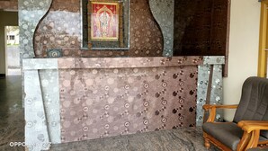 Un área de recepción con diseños de pared estampados, un icono religioso enmarcado y una silla de madera.