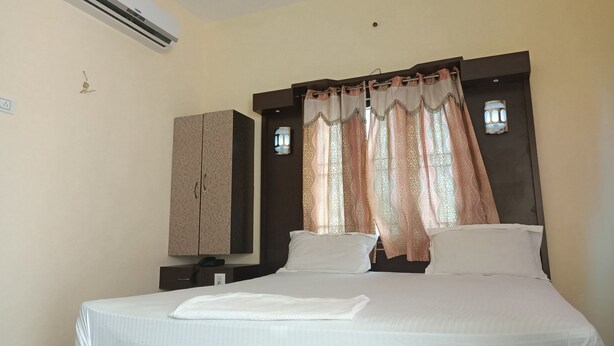 Una habitación de hotel con cama, aire acondicionado, armario y cortinas estampadas.