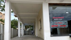 Un pasillo cubierto con columnas, un amplio ventanal con texto y un piso de concreto.
