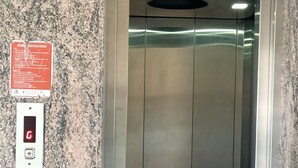 Un ascensor con pared de granito y señal de seguridad.
