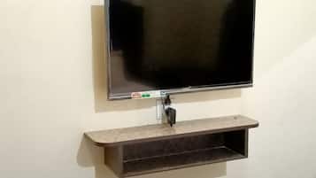 A flat-screen TV mounted on a wall with a shelf below it.