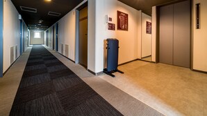 A long, narrow hallway with carpeted floors, recessed lighting, and doors on both sides. - Super Hotel Anjo (Anjo)