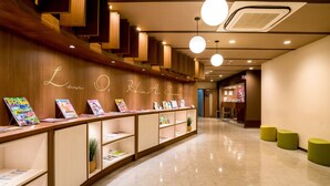 A modern hotel lobby with a wooden reception desk displaying magazines and a neon sign. - Super Hotel Anjo (Anjo)
