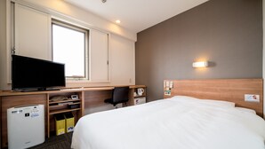 A hotel room with a bed, a desk with a television, a small refrigerator, a trash bin, and a window with blinds. - Super Hotel Anjo (Anjo)