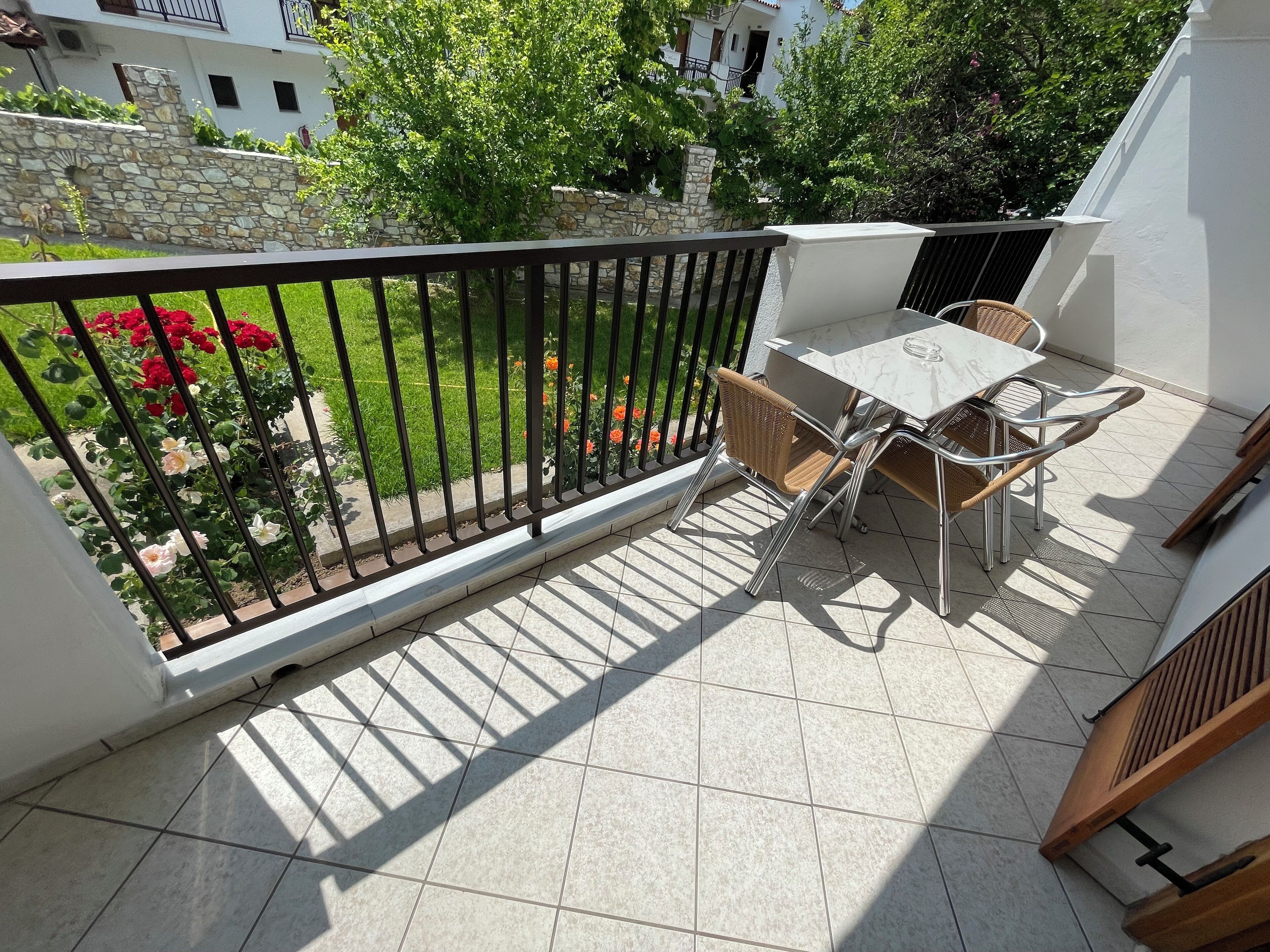Ein Balkon mit Fliesenboden, einem Tisch und Stühlen sowie einem Geländer.