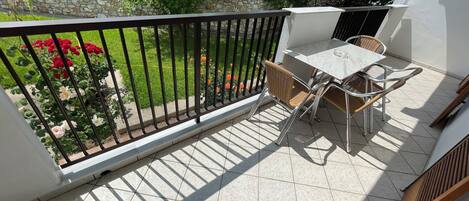A balcony with a tiled floor, a table with chairs, and a railing.