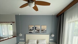 A bedroom with a bed, ceiling fan, artwork, bedside tables, and a window with curtains. - Adult Only - Hotel Suzanna (Skiathos)