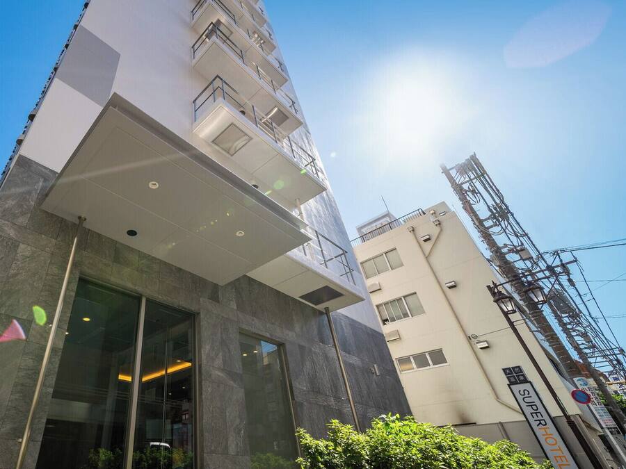 A modern hotel entrance with a glass facade, a flat roof, and a visible sign for the hotel.