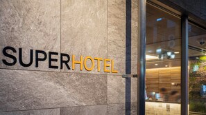 Un letrero de hotel con el nombre 'SUPERHOTEL' en letras negritas sobre una pared con textura.