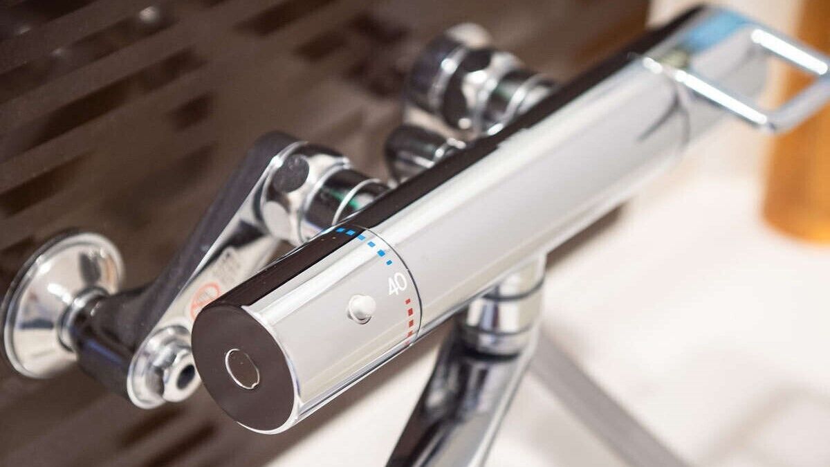 A metallic faucet with a control knob and a pressure adjustment feature.