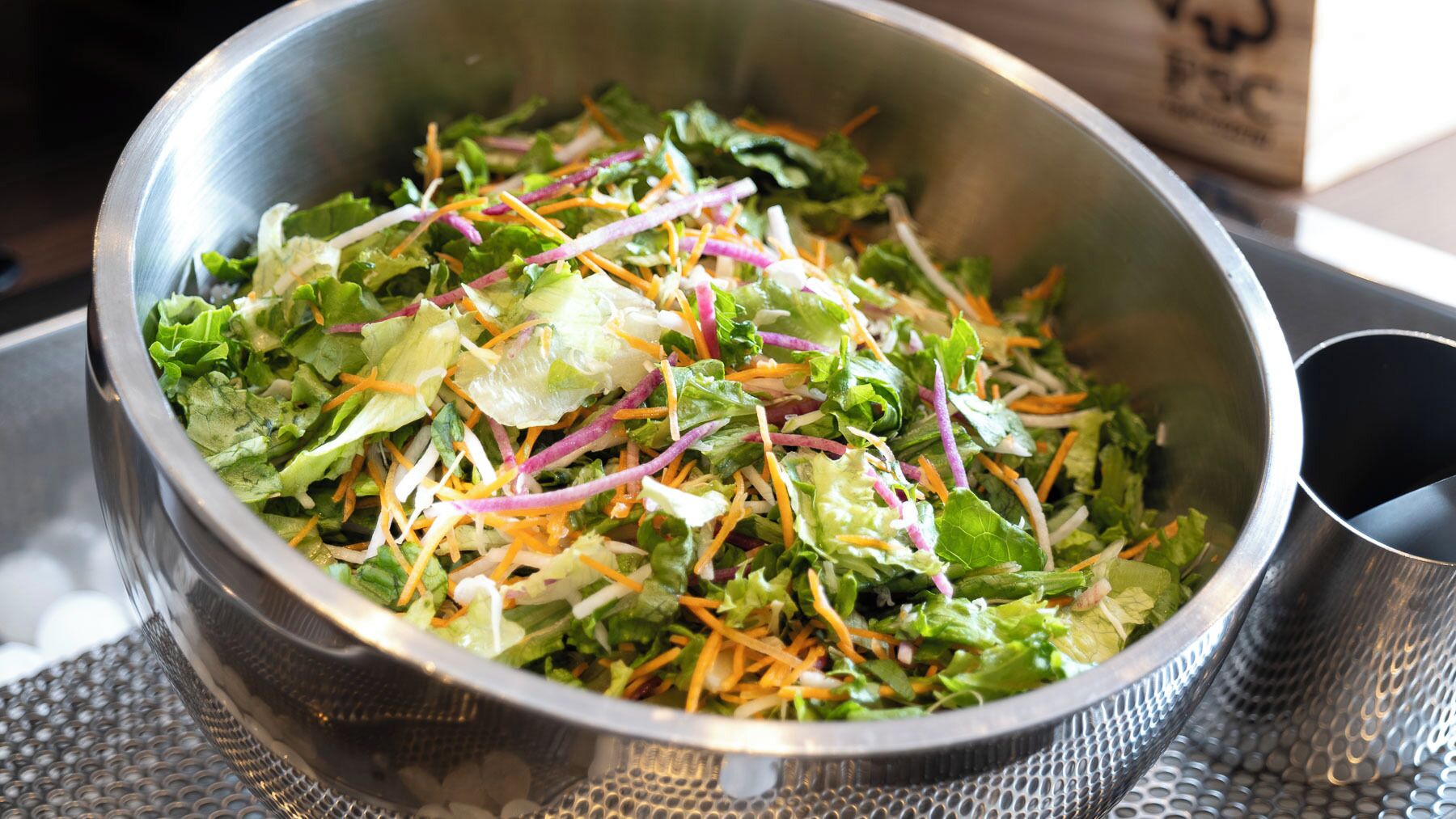 A stainless steel bowl filled with a salad.