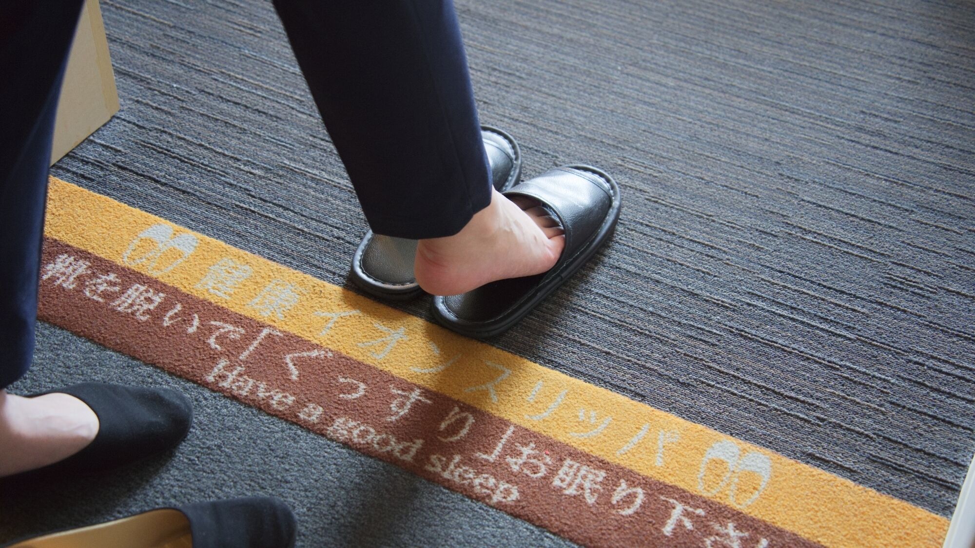 A person stepping on a floor with a sign with Japanese text.