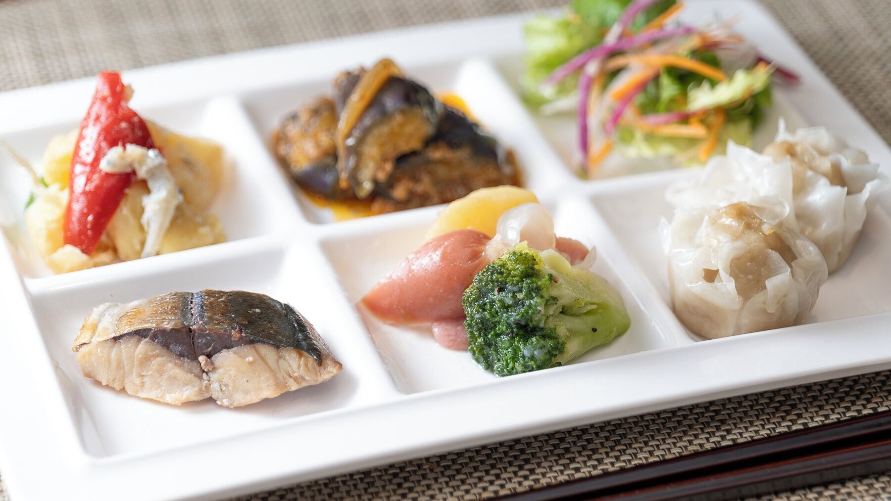 A meal with various dishes including fish, vegetables, and a salad.