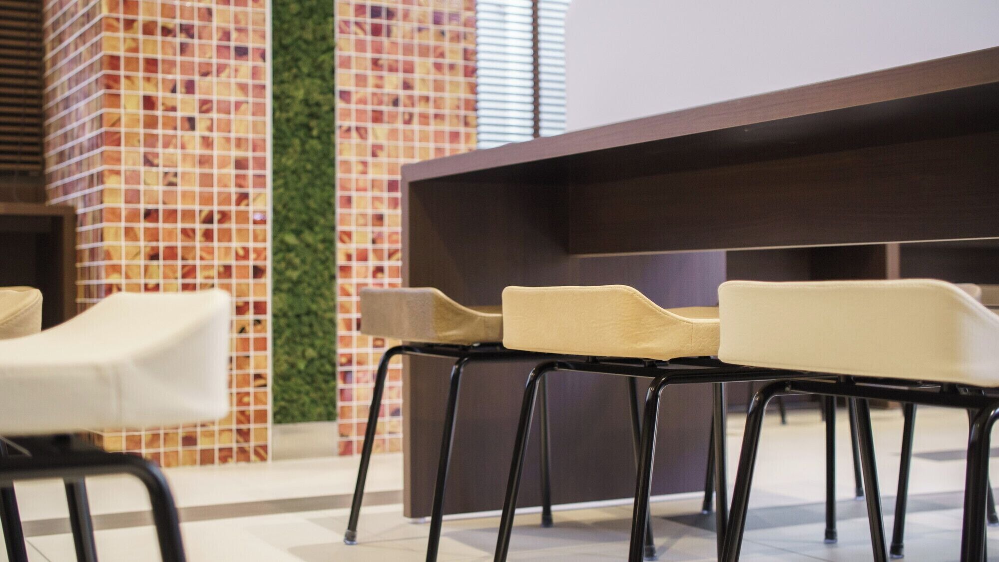 Un espace détente au design moderne, avec un mur en briques agrémenté d’un jardin vertical verdoyant et un comptoir d’accueil en bois foncé.