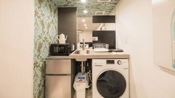 A compact kitchenette with a microwave, sink, and washing machine.