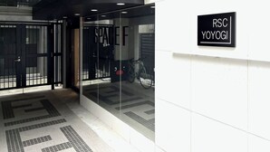 A modern building entrance with glass doors, a sign reading 'RSC YOYOGI', and a tiled floor pattern.