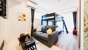 A modern living room with a sofa, a small table with a vase, a bunk bed, and a TV.