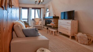 Una sala de estar acogedora con un sofá, una mesita, un televisor y una chimenea.