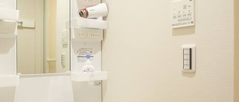 A bathroom with a white sink, a mirror, a towel dispenser, and a wall-mounted light switch.
