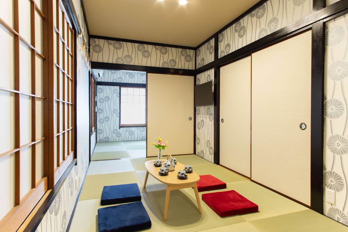 A traditional Japanese room with tatami flooring, a low wooden table with tea sets, and shoji screens.