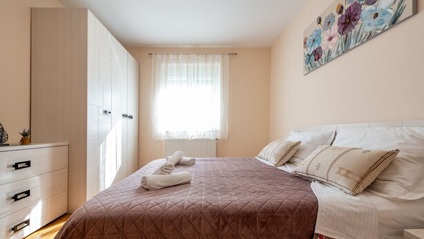 A bedroom with a bed, a dresser, a window with curtains, and a painting on the wall. - Villa Balen (Benkovac)