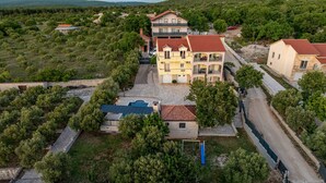 An aerial view of a residential area with multiple houses, a swimming pool, and a paved road. - Villa Balen (Benkovac)
