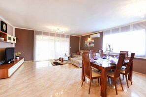 Una sala de estar moderna con comedor, sofá, televisor y chimenea.