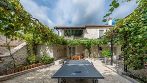 Ein Tischtennistisch in einem Innenhof mit Steinmauern und viel Grün.