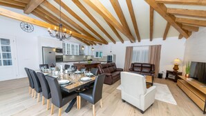 A spacious living area with a dining table set for six, a sofa, and a TV stand. - Villa Idassa (Policnik)