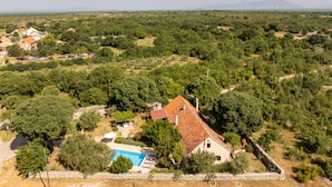 An aerial view of a property with a swimming pool, surrounded by trees and a mountainous backdrop. - Villa Krasa (Promina)