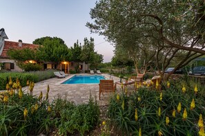 A pool area with lounge chairs, a wooden deck, and a stone pathway. - Villa Krasa (Promina)