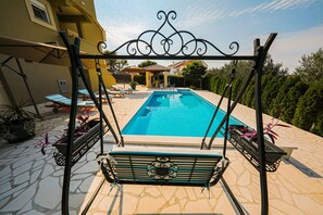 A swimming pool with lounge chairs and a pergola structure.