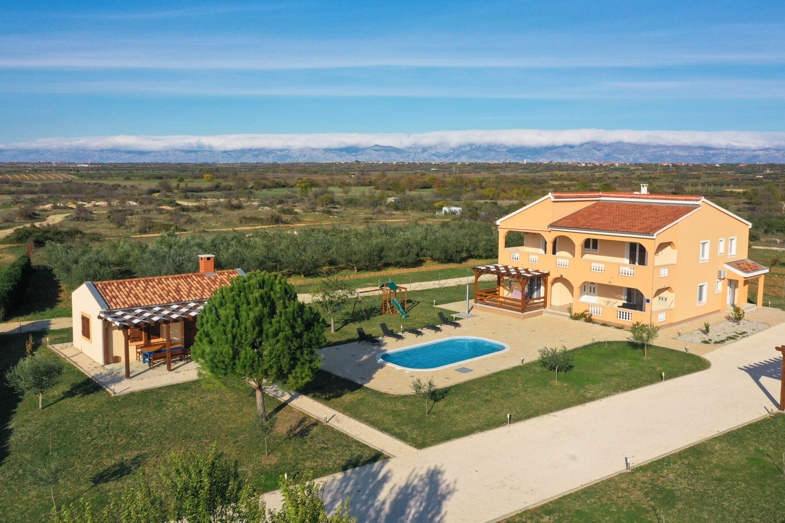 Una casa de dos plantas con piscina, patio y vistas a las montañas.
