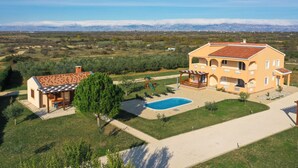 Una casa de dos plantas con piscina, patio y vistas a las montañas.