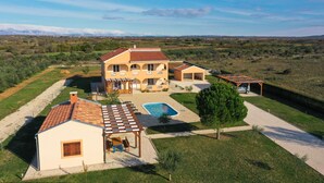 Una casa grande con piscina, varias habitaciones y un espacio exterior cubierto.