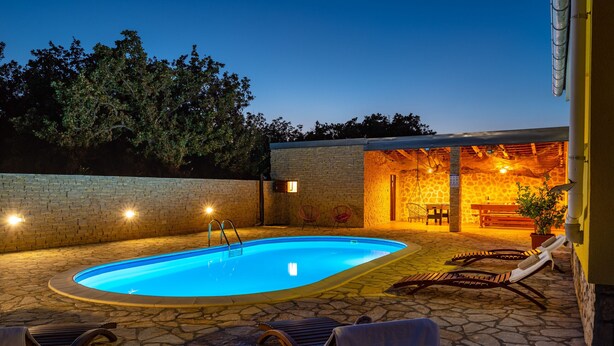 A swimming pool with lounge chairs and a brick wall. - Villa Didov Dvor (Posedarje)