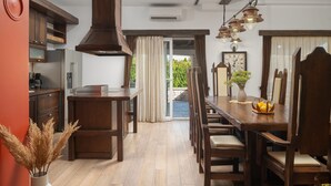 A dining area with a wooden table and chairs, a vase with dried plants, and a view through a glass door to an outdoor space. - Villa Quince (Policnik)