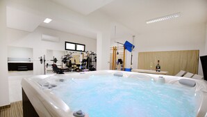 A modern spa room with a hot tub, exercise equipment, and a wooden ladder for accessing the tub. - Villa Quince (Policnik)