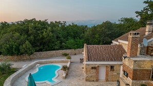 Une villa en pierre dotée d’une piscine, d’un espace salon extérieur et d’un mur en pierre.